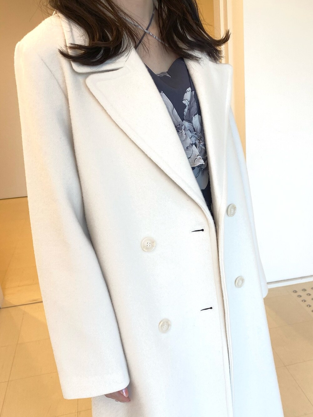 ホワイト系のチェスターコート、グレー系のワンピース、ブラック系のハンドバッグを着用したレディースの秋コーディネートの5枚目の写真