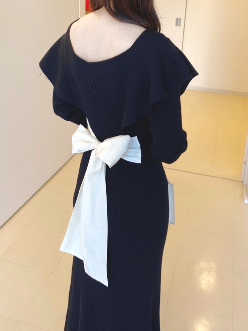 ブラック系のワンピース、ホワイト系のハンドバッグ、ブラウン系のブーツを着用したレディースの冬コーディネートの6枚目の写真