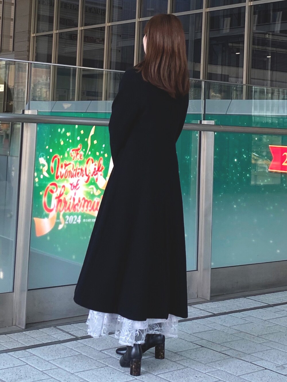 ブラック系のその他アウター、ホワイト系のニット/セーター、ブラック系のブーツを着用したレディースの秋コーディネートの3枚目の写真