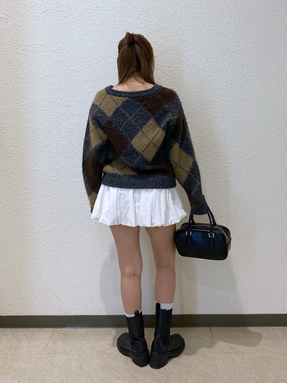 ホワイト系のスカート、ブラック系のハンドバッグを着用したレディースの冬コーディネートの3枚目の写真