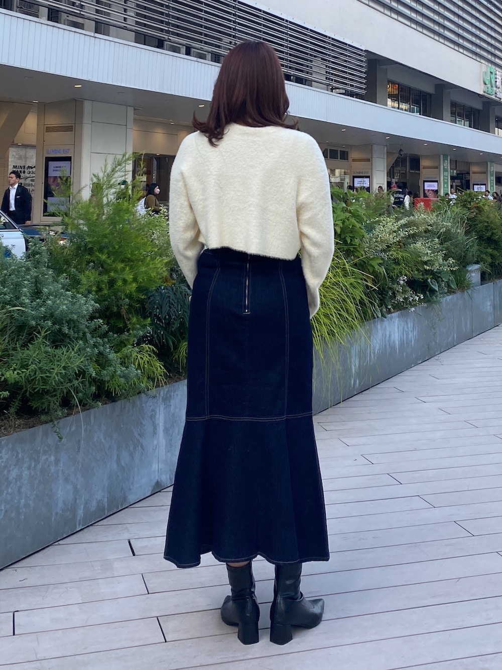 ホワイト系のニット/セーター、ブルー系のデニムスカート、ブラック系のブーツを着用したレディースの秋コーディネートの3枚目の写真