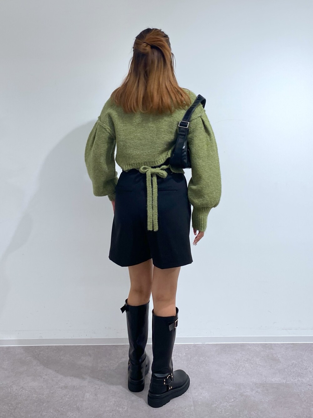 グリーン系のニット/セーター、ブラウン系のブーツ、ブラック系のその他パンツを着用したレディースの秋コーディネートの2枚目の写真