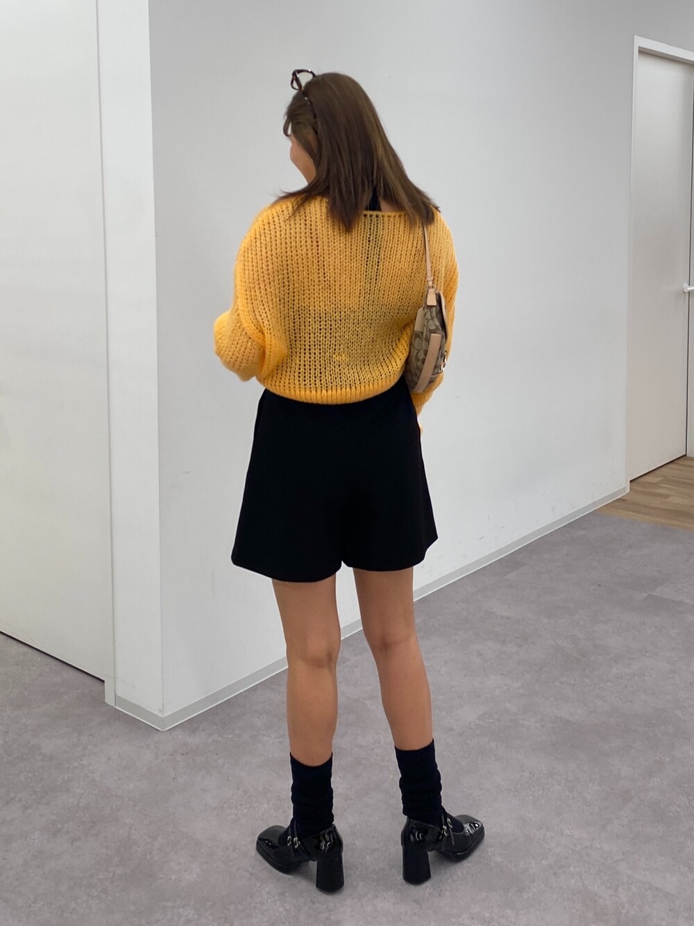 オレンジ系のニット/セーター、ブラック系のその他パンツ、ブラック系のパンプスを着用したレディースの冬コーディネートの3枚目の写真