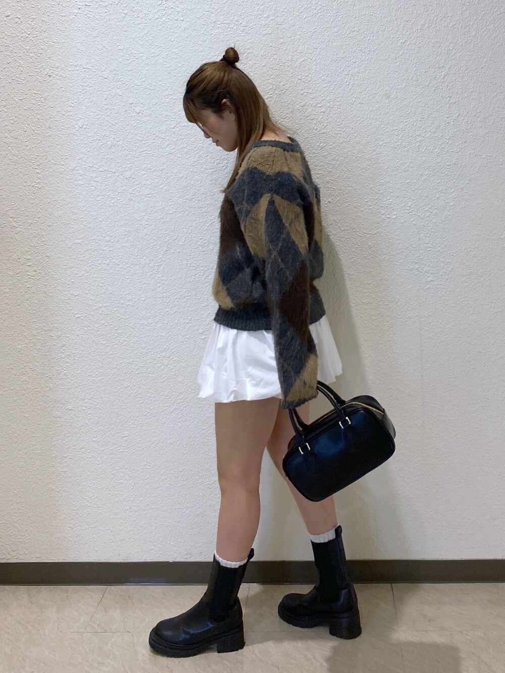 ホワイト系のスカート、ブラック系のハンドバッグを着用したレディースの冬コーディネートの2枚目の写真