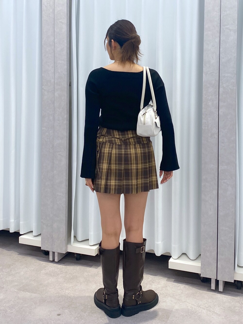 ブラック系のニット/セーター、ブラウン系のスカート、ブラウン系のブーツを着用したレディースの冬コーディネートの2枚目の写真