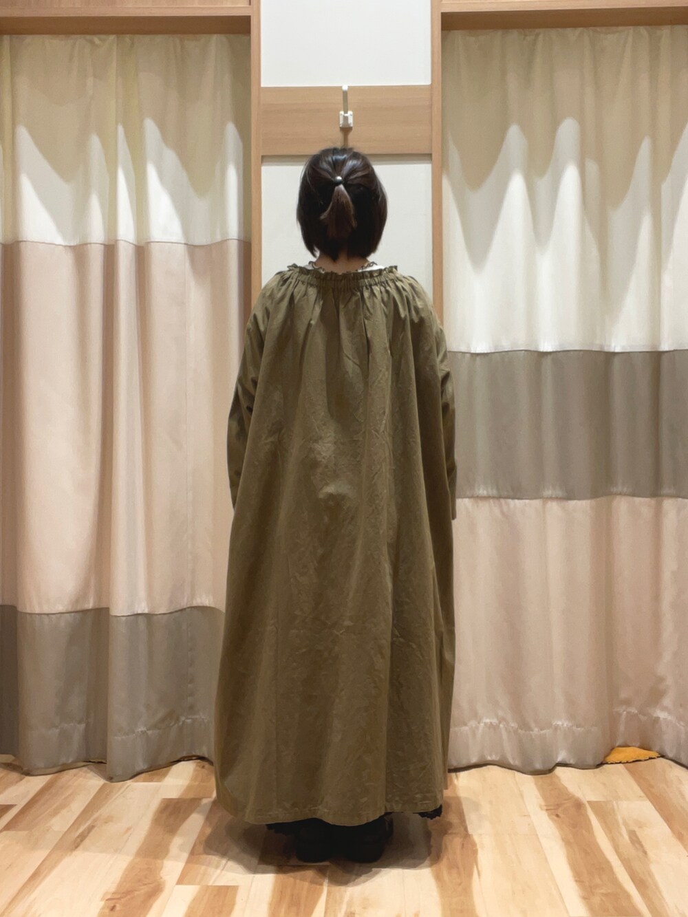 グリーン系のワンピース、ブラック系のスカート、ホワイト系のTシャツ/カットソーを着用したレディースの秋コーディネートの2枚目の写真