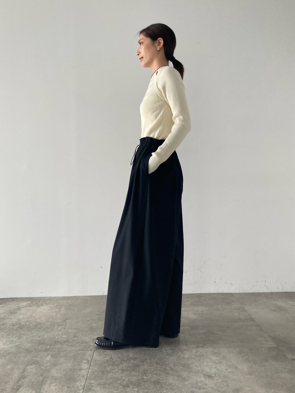 ブラック系のその他パンツ、ホワイト系のニット/セーターを着用したレディースの秋コーディネートの2枚目の写真