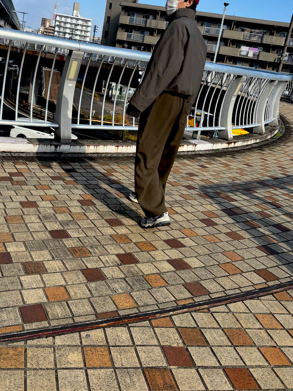 ブラック系のボディバッグ/ウエストポーチ、ブラック系のスニーカー、グリーン系のジャケット/アウターを着用したレディースの秋コーディネートの2枚目の写真