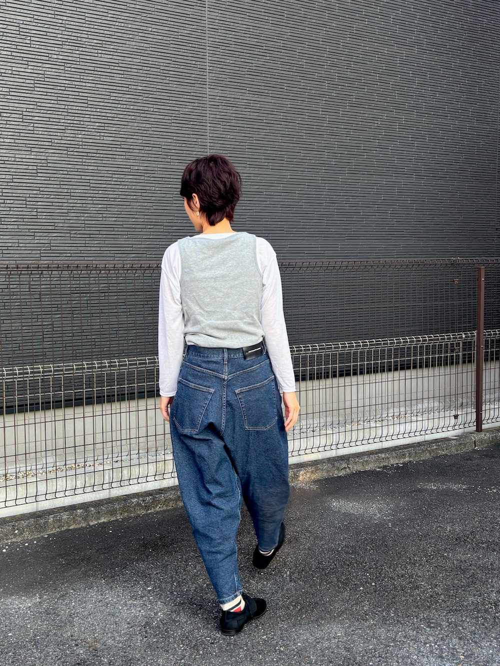 ブルー系のデニムパンツ、ブラック系のローファー、ホワイト系のトップスを着用したレディースの秋コーディネートの2枚目の写真