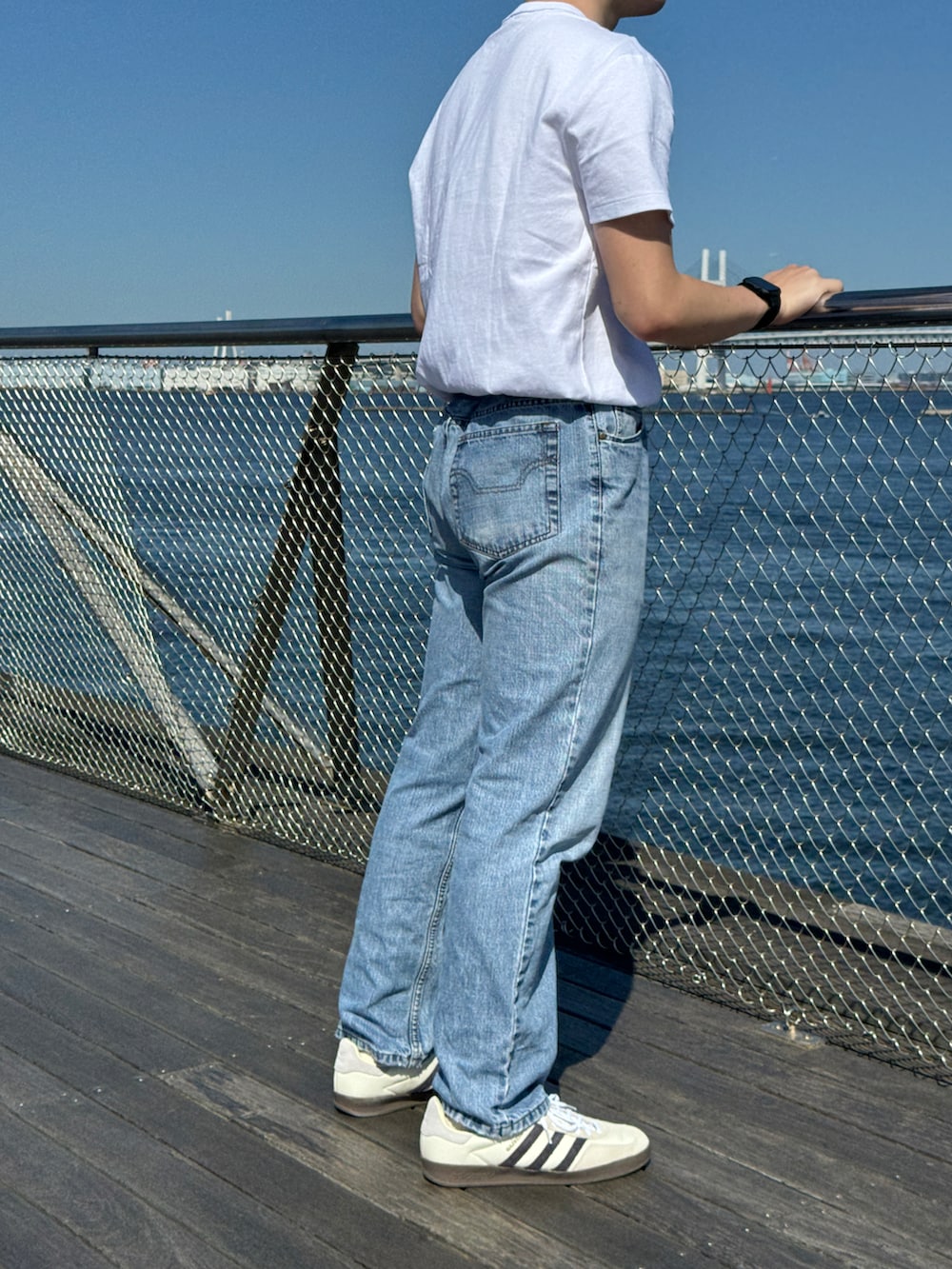 ホワイト系のTシャツ/カットソー、ブルー系のデニムパンツ、ホワイト系のスニーカーを着用したメンズの夏コーディネートの2枚目の写真