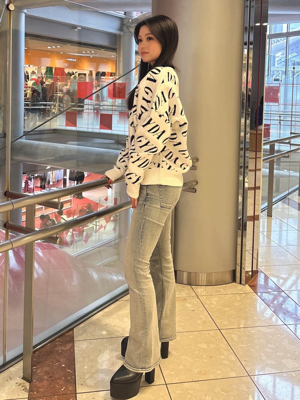 ブラック系のニット/セーター、ブルー系のデニムパンツ、ブラック系のブーツを着用したレディースの春コーディネートの2枚目の写真