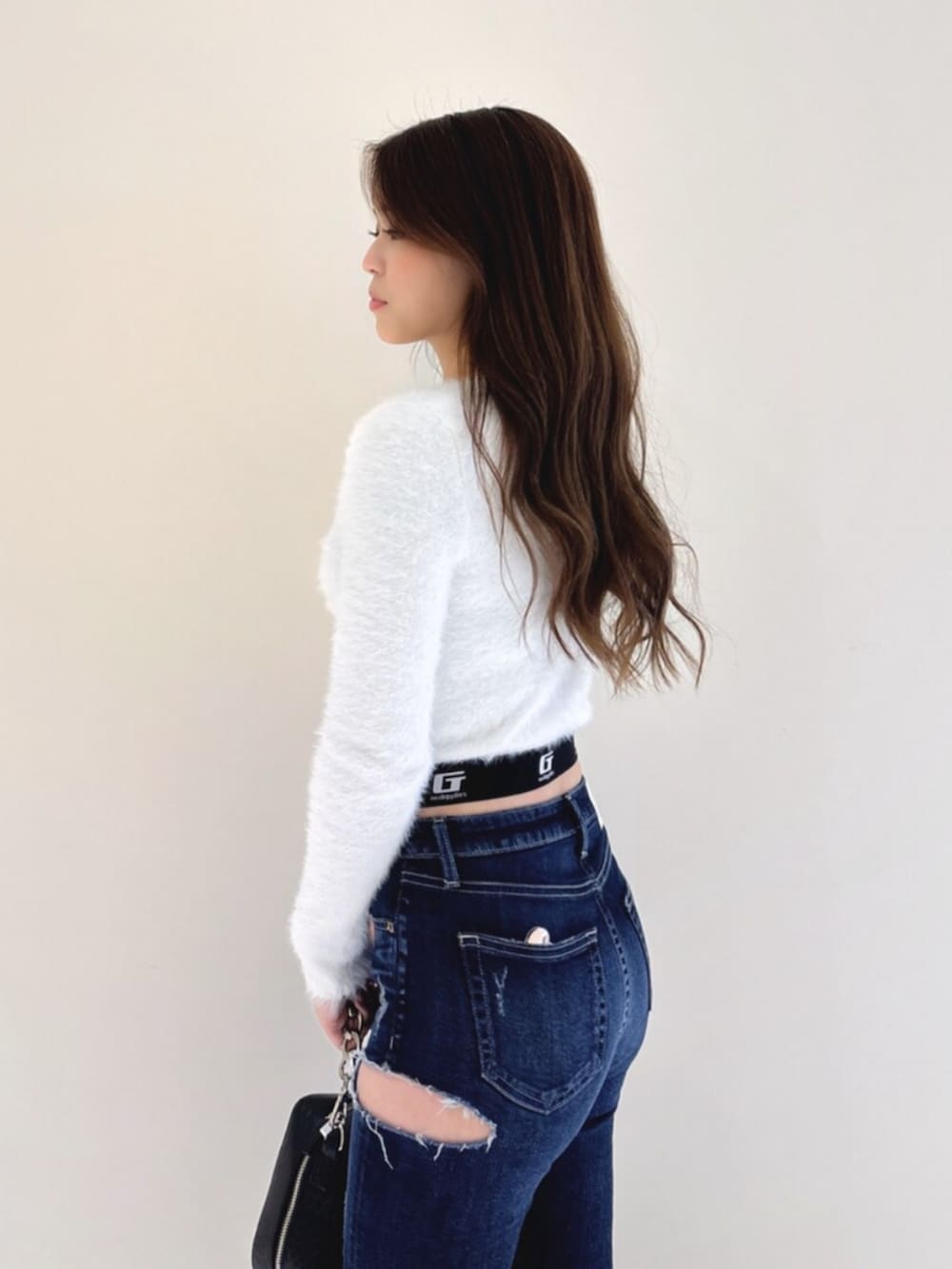 ホワイト系のパンプス、ブルー系のデニムパンツ、ブラック系のショルダーバッグを着用したレディースの冬コーディネートの7枚目の写真