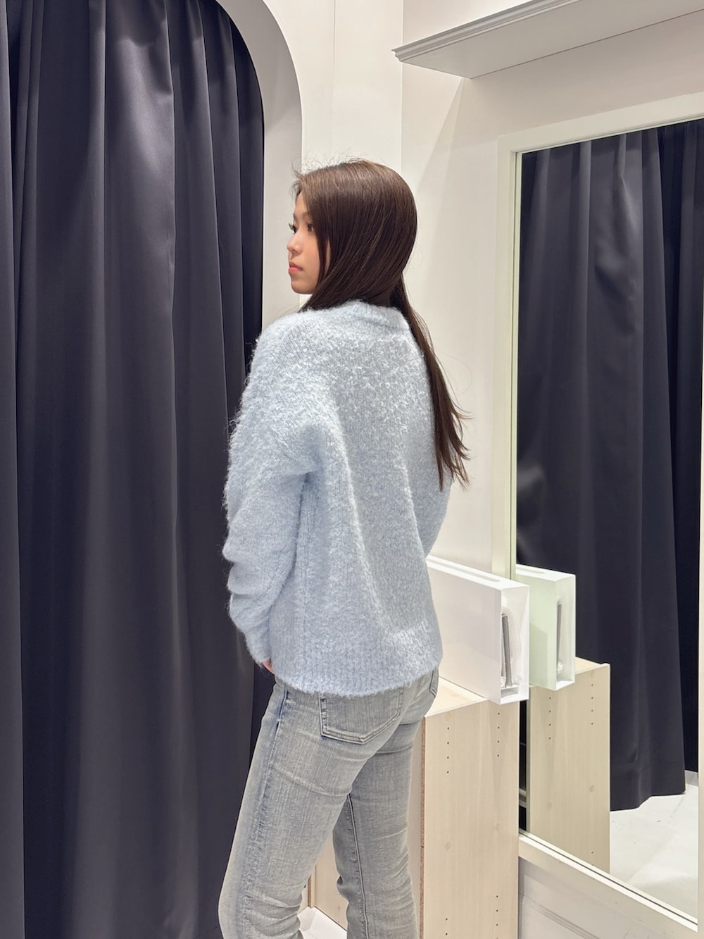 ブルー系のニット/セーター、ブルー系のデニムパンツ、ブラック系のブーツを着用したレディースの冬コーディネートの5枚目の写真