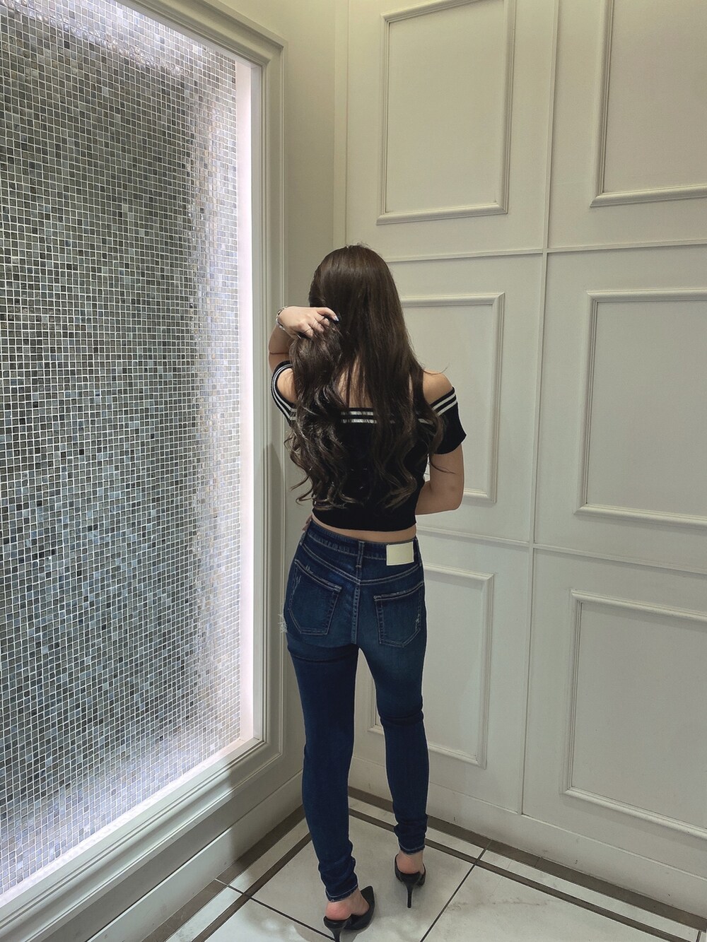 ブラック系のニット/セーター、ブルー系のデニムパンツ、ブラック系のパンプスを着用したレディースの夏コーディネートの3枚目の写真