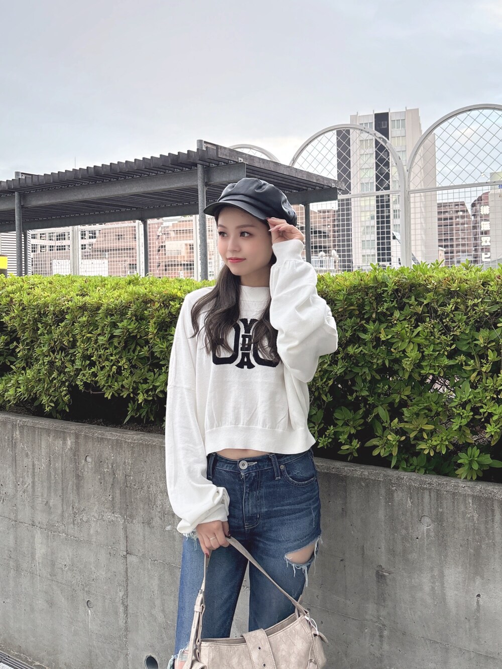 ホワイト系のニット/セーター、ブルー系のデニムパンツ、ベージュ系のショルダーバッグを着用したレディースの秋コーディネートの6枚目の写真