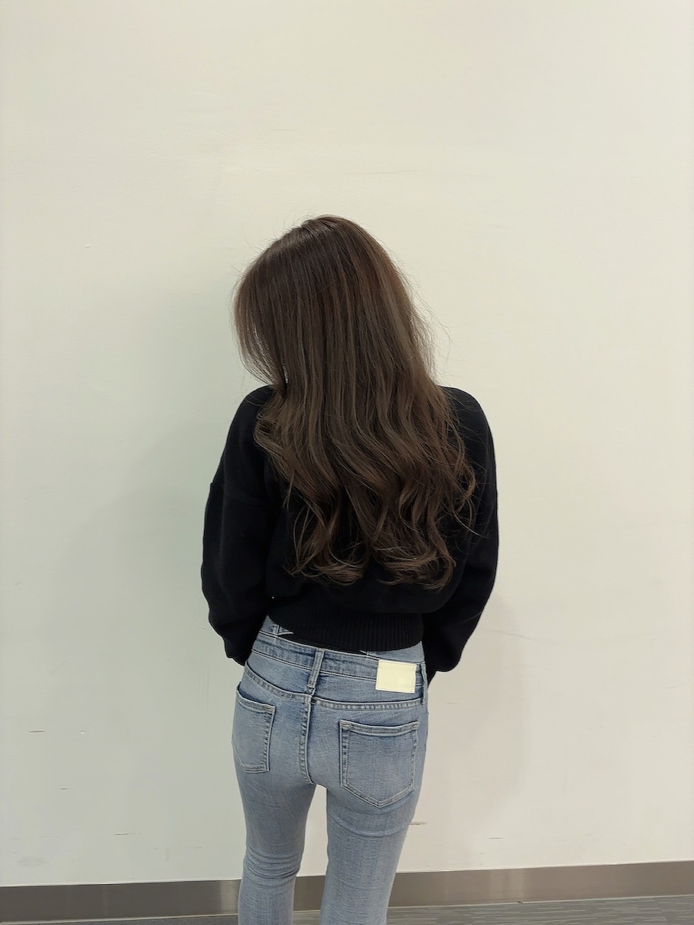 ブラック系のニット/セーター、ブルー系のデニムパンツ、ブラック系のブーツを着用したレディースの冬コーディネートの5枚目の写真