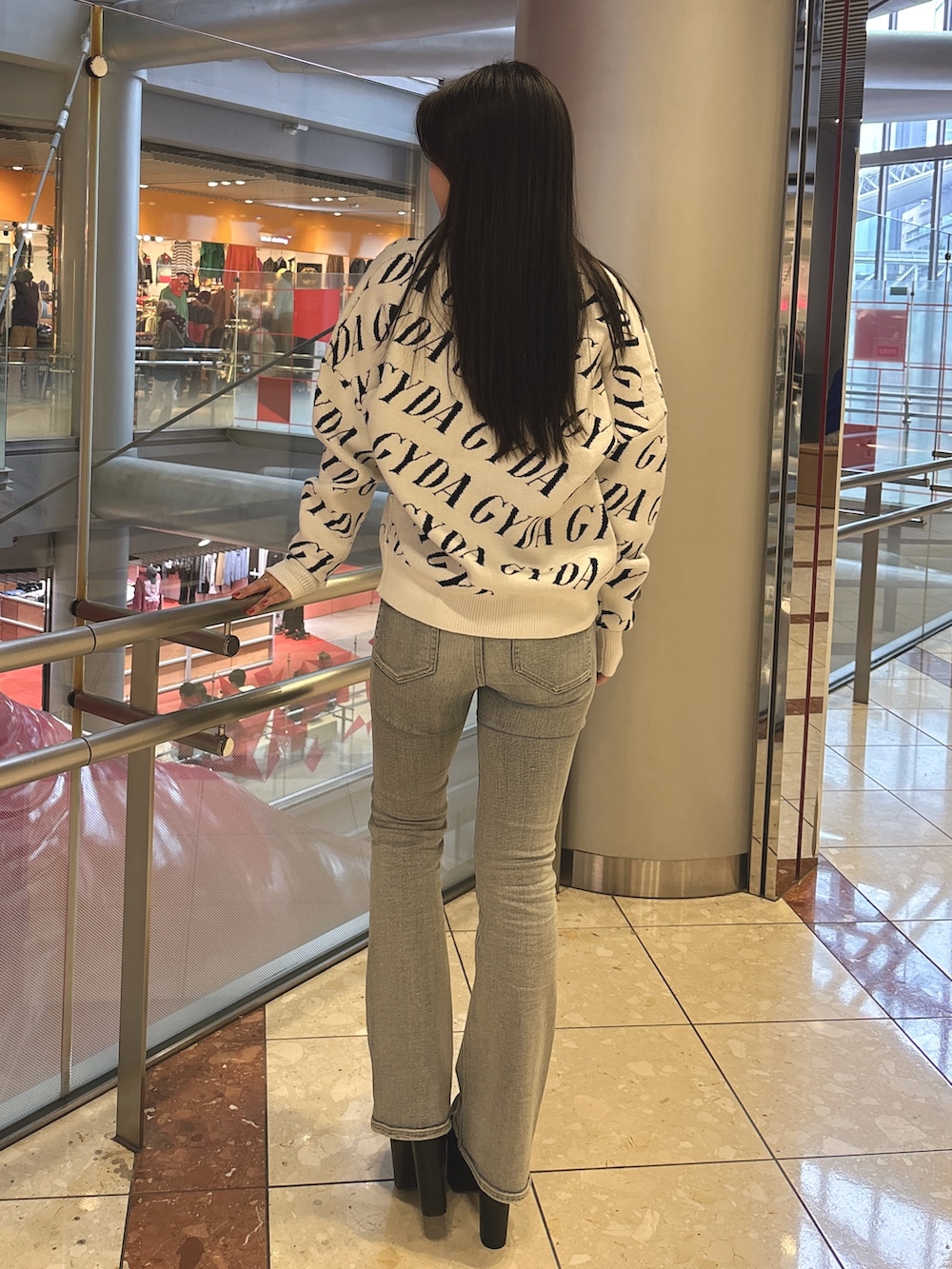 ブラック系のニット/セーター、ブルー系のデニムパンツ、ブラック系のブーツを着用したレディースの春コーディネートの3枚目の写真