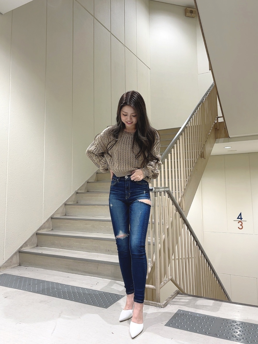 ベージュ系のニット/セーター、ブルー系のデニムパンツ、ホワイト系のパンプスを着用したレディースの冬コーディネートの2枚目の写真