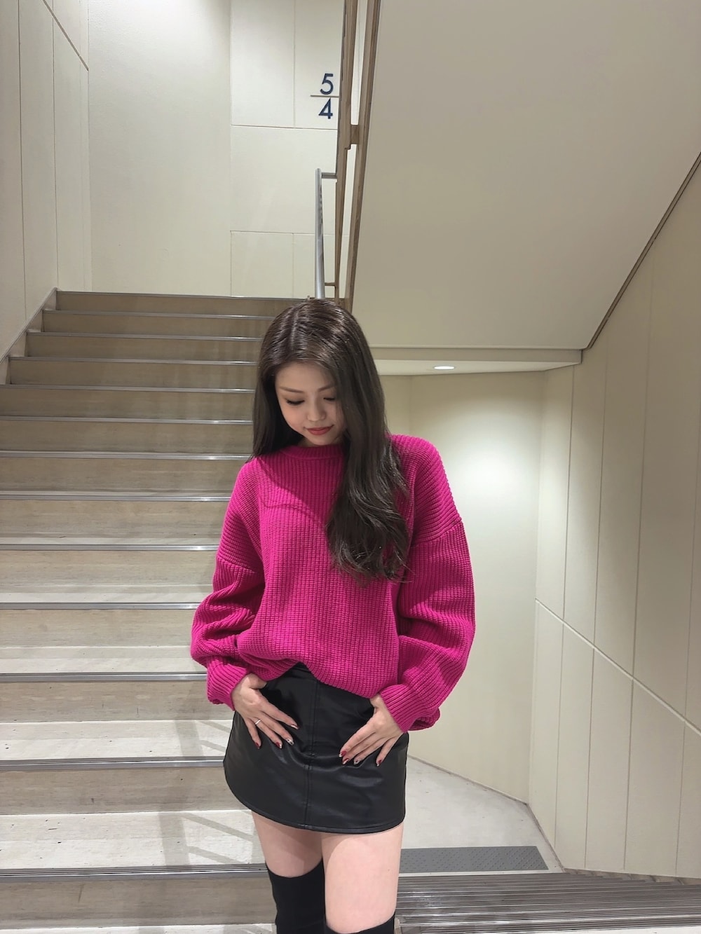 ピンク系のニット/セーター、ブラック系のスカート、ブラック系のブーツを着用したレディースの秋コーディネートの4枚目の写真