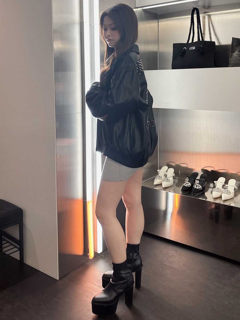 シルバー系のワンピース、ブラック系のブーツ、ブラック系のブルゾンを着用したレディースの春コーディネートの2枚目の写真