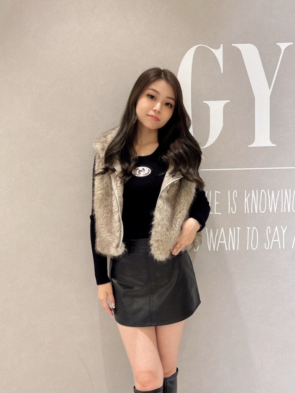 ブラック系のニット/セーター、ブラック系のスカート、ブラック系のブーツを着用したレディースの秋コーディネートの4枚目の写真