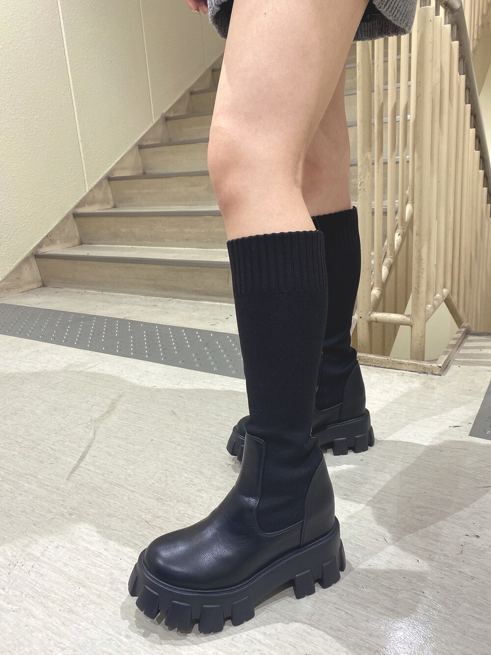 グレー系のニット/セーター、ブラック系のブーツを着用したレディースの秋コーディネートの6枚目の写真