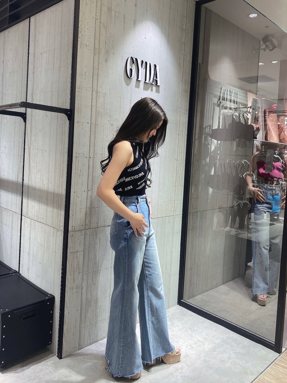 ブラック系のニット/セーター、ホワイト系のサンダル、ブルー系のデニムパンツを着用したレディースの春コーディネートの3枚目の写真