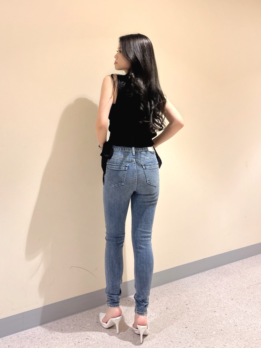 ブラック系のニット/セーター、ブルー系のデニムパンツ、ホワイト系のパンプスを着用したレディースの夏コーディネートの4枚目の写真