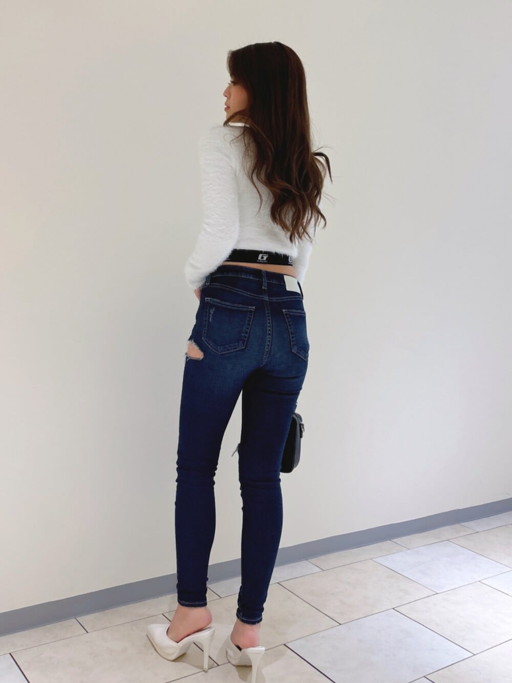 ホワイト系のパンプス、ブルー系のデニムパンツ、ブラック系のショルダーバッグを着用したレディースの冬コーディネートの4枚目の写真