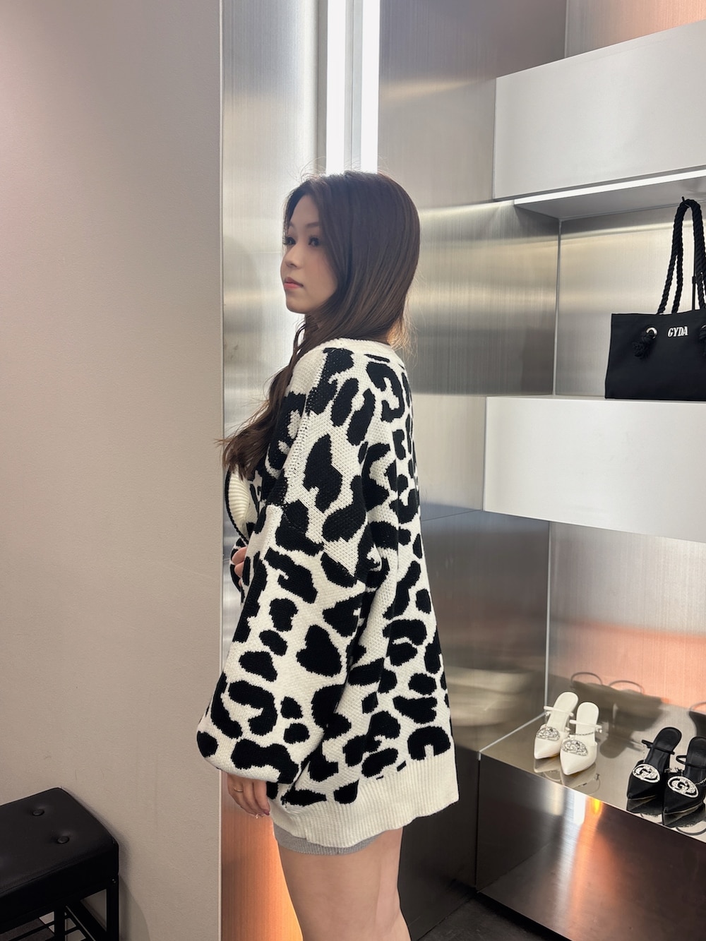 ブラック系のブーツ、ホワイト系のカーディガン/ボレロ、シルバー系のワンピースを着用したレディースの春コーディネートの5枚目の写真