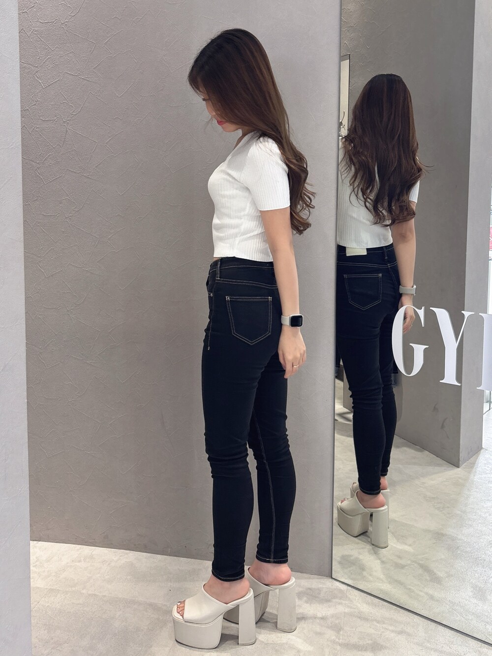 ホワイト系のニット/セーター、ブラック系のデニムパンツ、ホワイト系のサンダルを着用したレディースの夏コーディネートの2枚目の写真