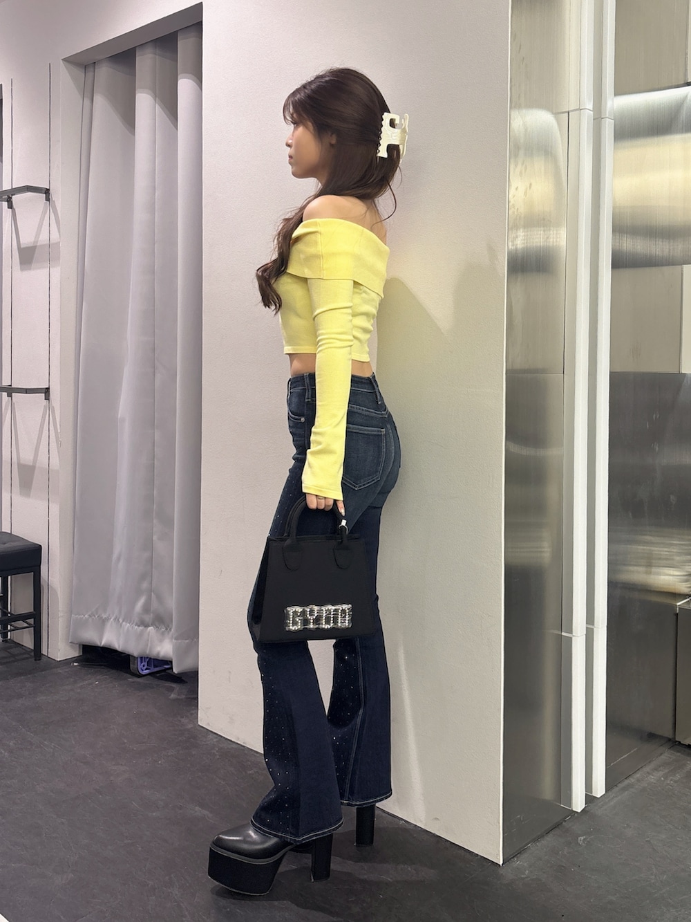 イエロー系のニット/セーター、ブラック系のハンドバッグ、ブルー系のデニムパンツを着用したレディースの秋コーディネートの2枚目の写真