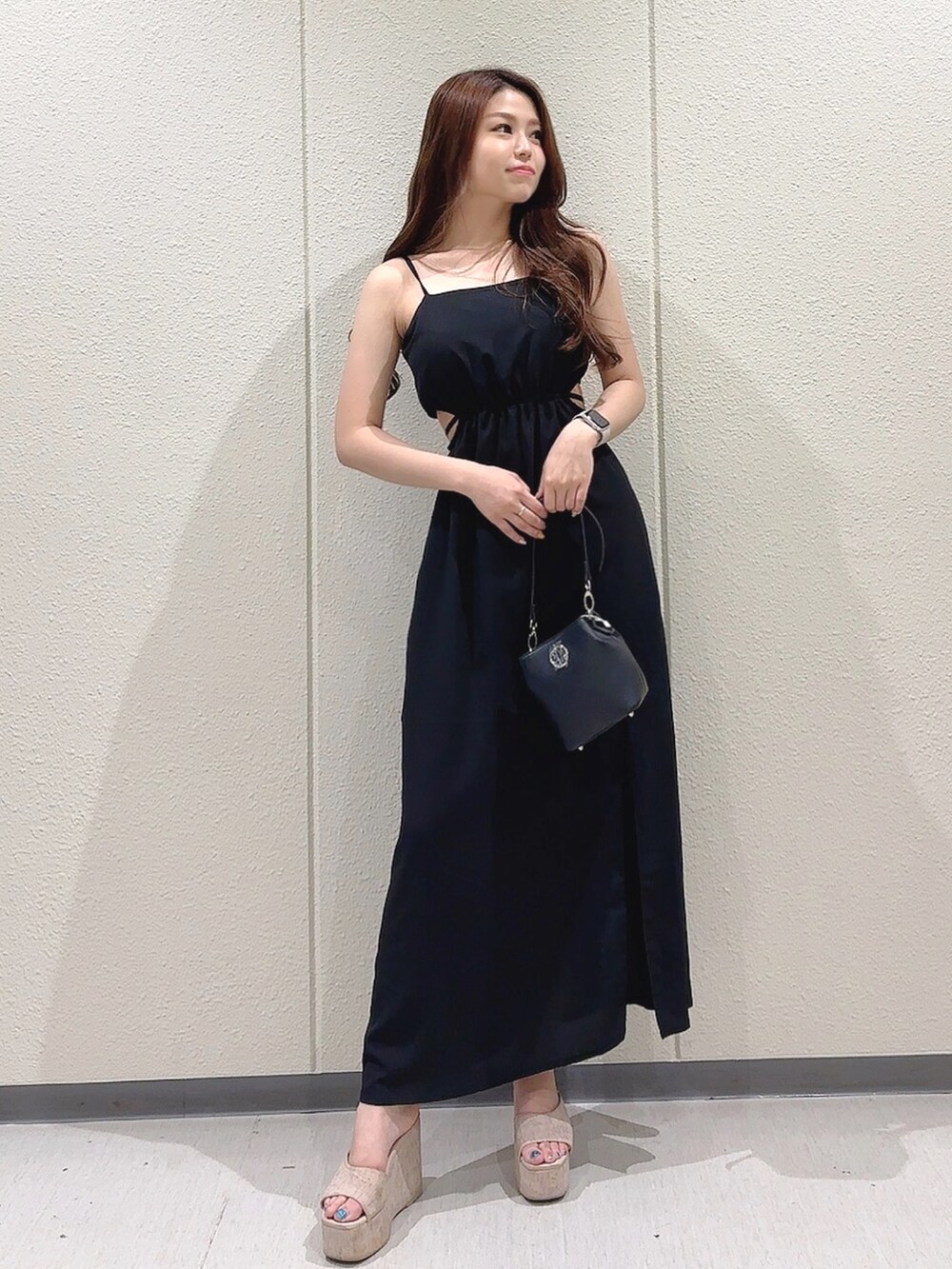 ブラック系のワンピース、ブラック系のショルダーバッグ、ホワイト系のサンダルを着用したレディースの夏コーディネートの2枚目の写真