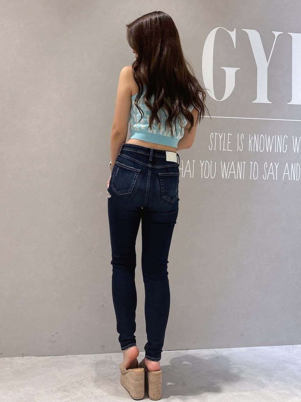 グリーン系のニット/セーター、ブルー系のデニムパンツ、ホワイト系のサンダルを着用したレディースの春コーディネートの3枚目の写真