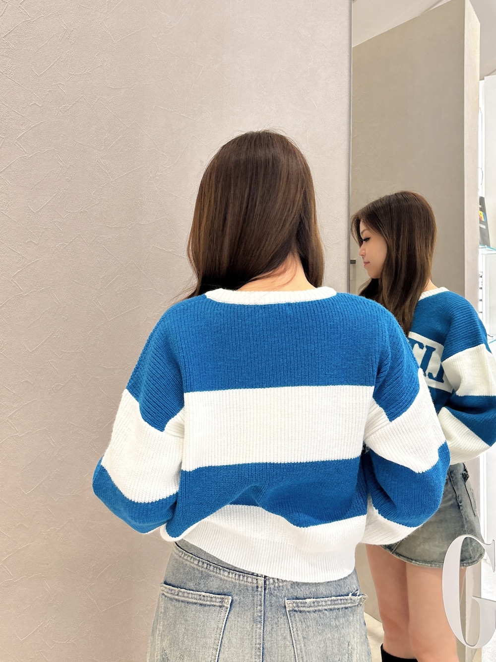 ブルー系のニット/セーター、ブルー系のデニムスカート、ブラック系のブーツを着用したレディースの秋コーディネートの6枚目の写真