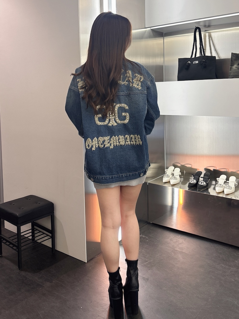 ブラック系のブーツ、シルバー系のワンピース、ブルー系のデニムジャケットを着用したレディースの春コーディネートの3枚目の写真