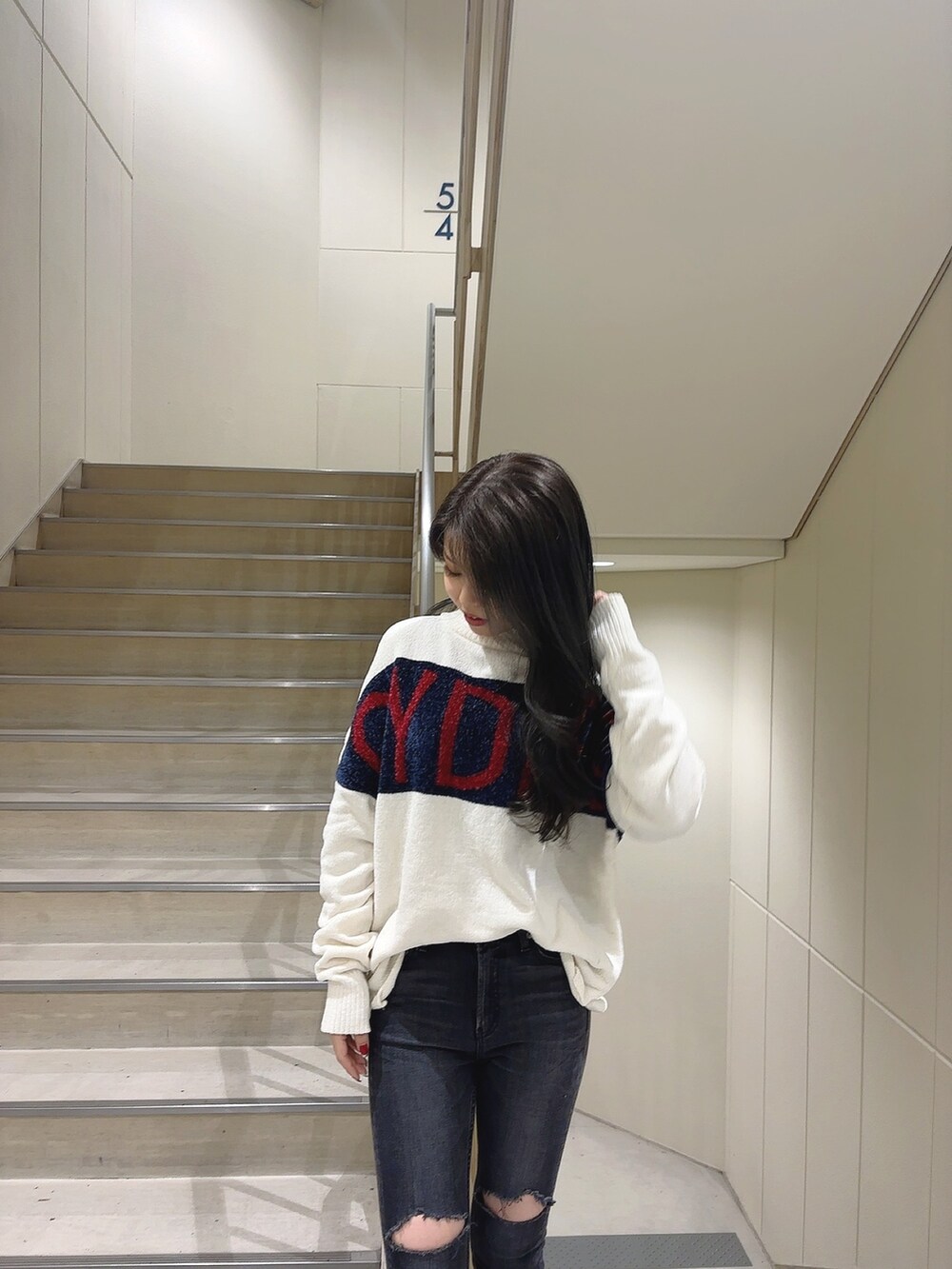 ホワイト系のニット/セーター、ブラック系のデニムパンツ、ブラック系のブーツを着用したレディースの秋コーディネートの4枚目の写真