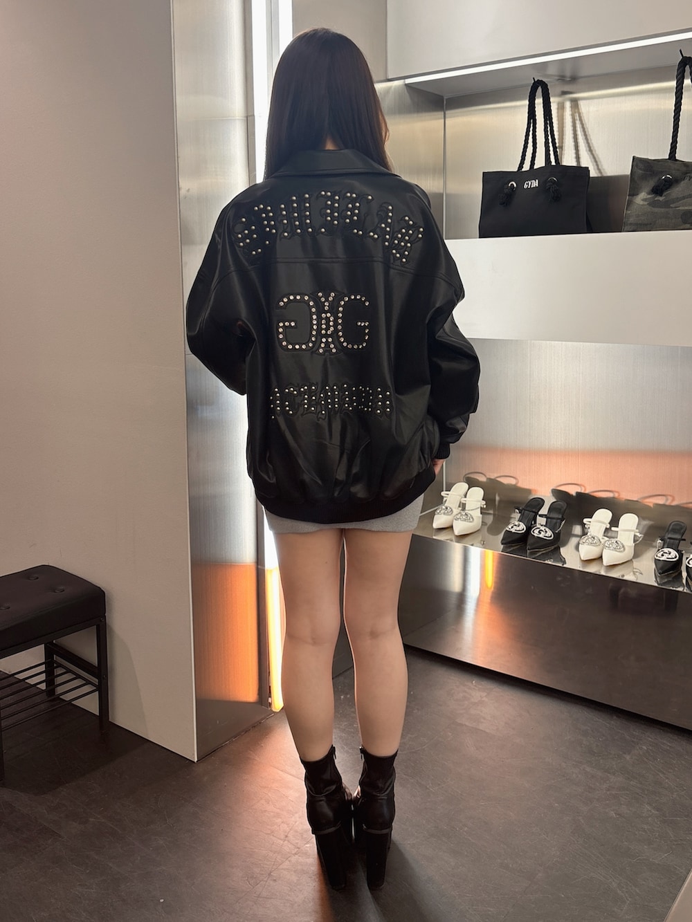 シルバー系のワンピース、ブラック系のブーツ、ブラック系のブルゾンを着用したレディースの春コーディネートの3枚目の写真