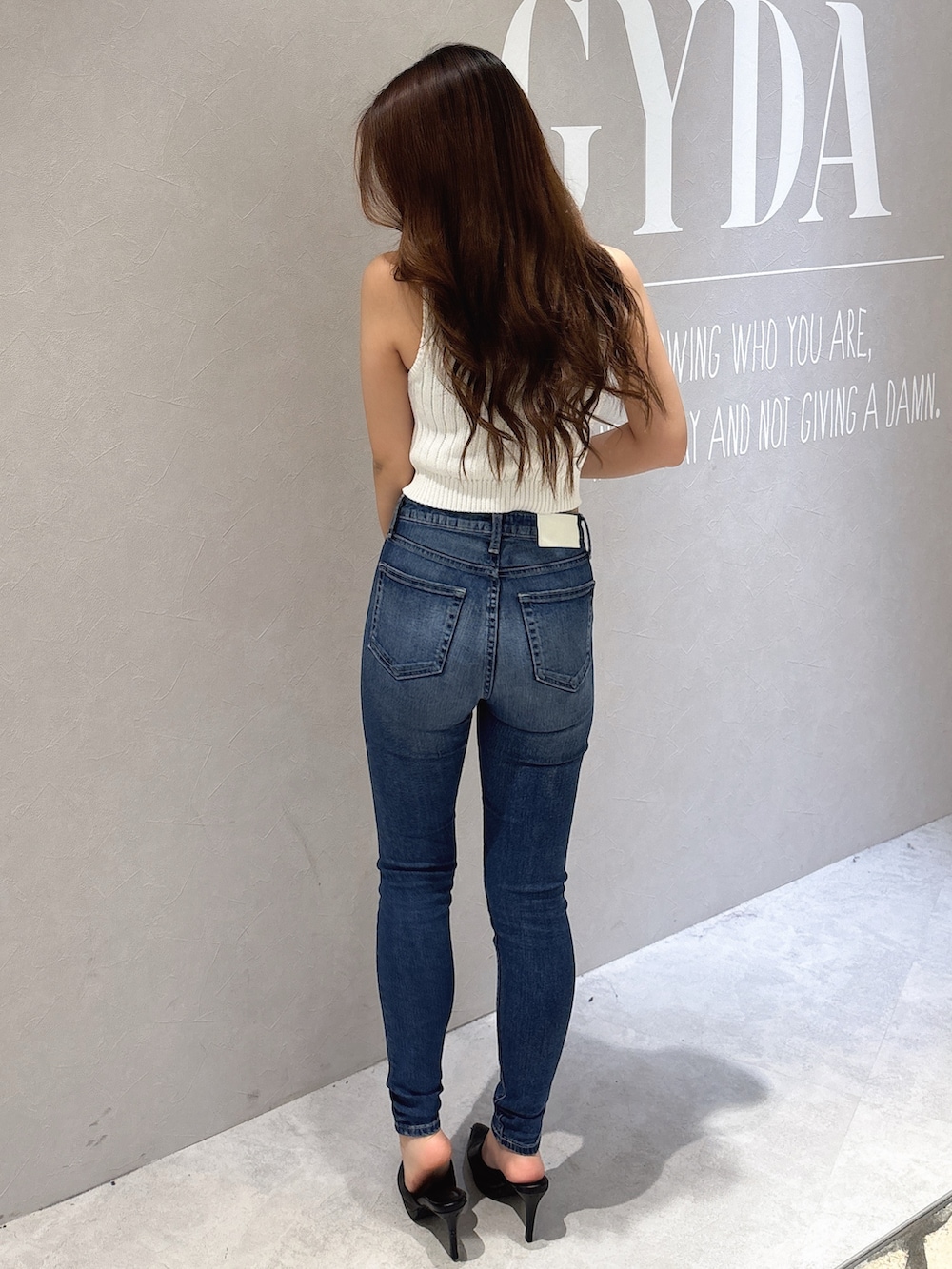 ホワイト系のニット/セーター、ブルー系のデニムパンツ、ホワイト系のパンプスを着用したレディースの夏コーディネートの3枚目の写真