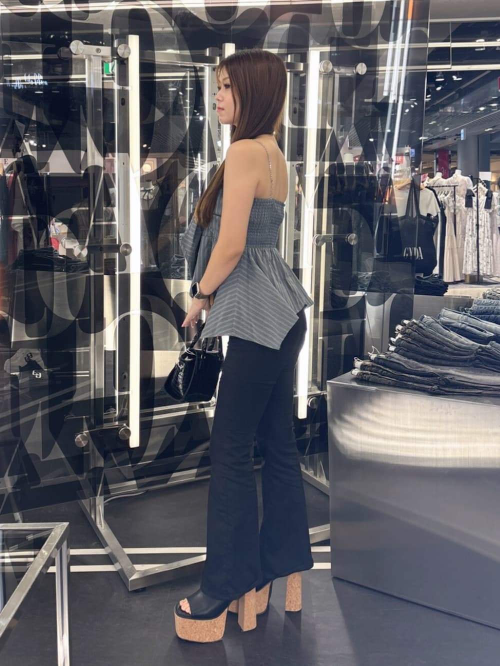 ブルー系のデニムパンツ、ホワイト系のサンダル、ホワイト系のハンドバッグを着用したレディースの夏コーディネートの2枚目の写真