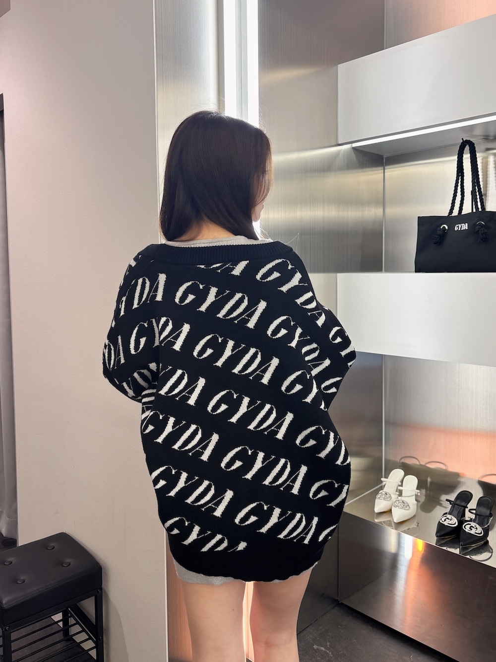 ブラック系のカーディガン/ボレロ、シルバー系のワンピース、ブラック系のブーツを着用したレディースの春コーディネートの6枚目の写真