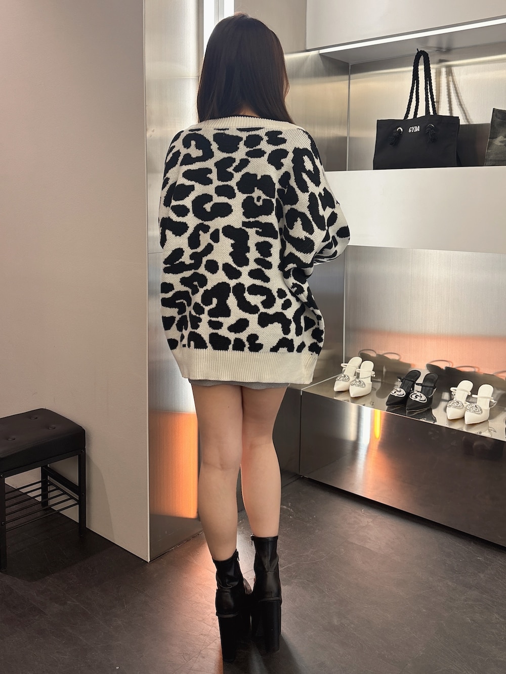 ブラック系のブーツ、ホワイト系のカーディガン/ボレロ、シルバー系のワンピースを着用したレディースの春コーディネートの3枚目の写真