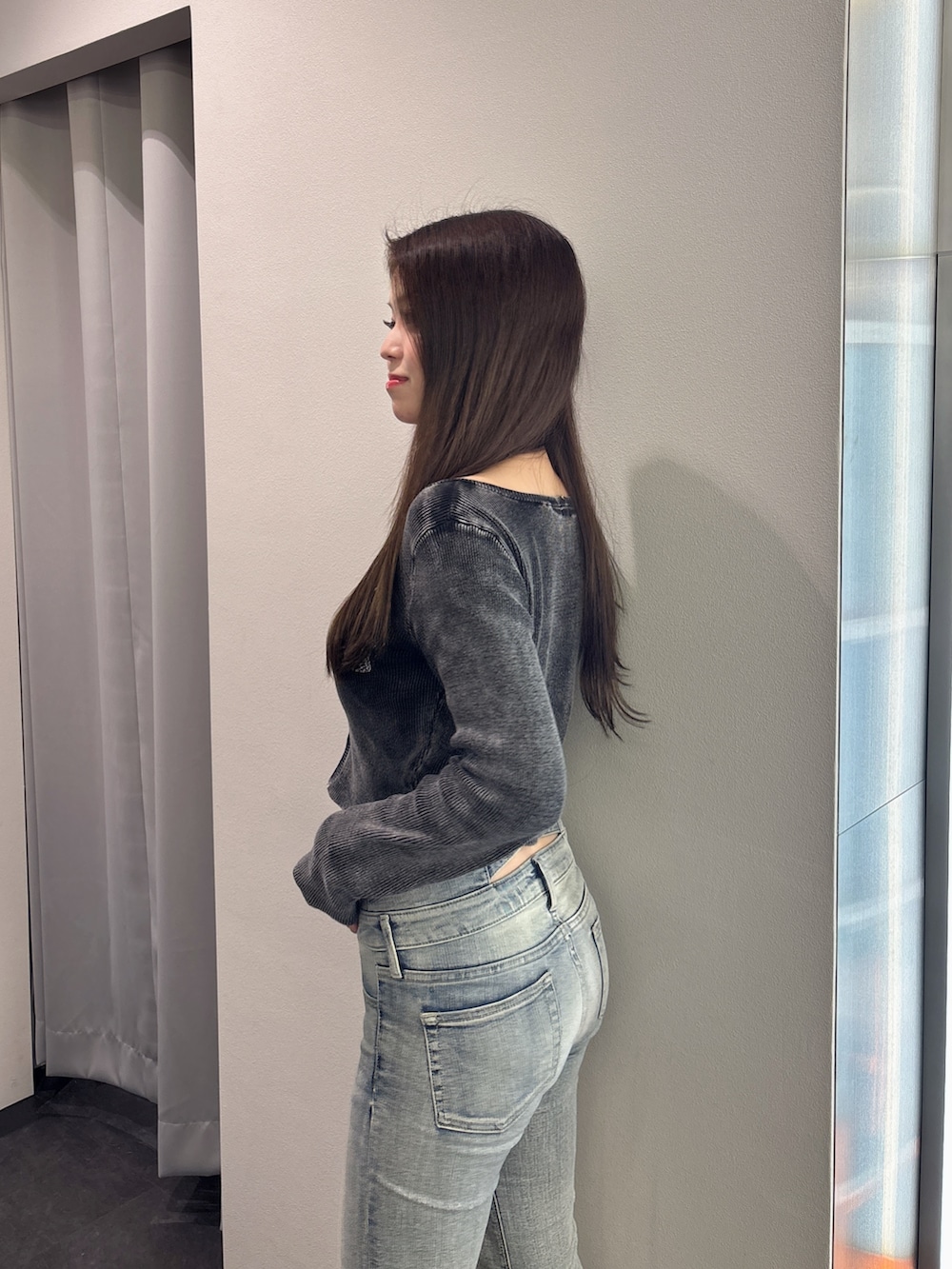 ブラック系のニット/セーター、ブルー系のデニムパンツ、ブラック系のブーツを着用したレディースの春コーディネートの5枚目の写真