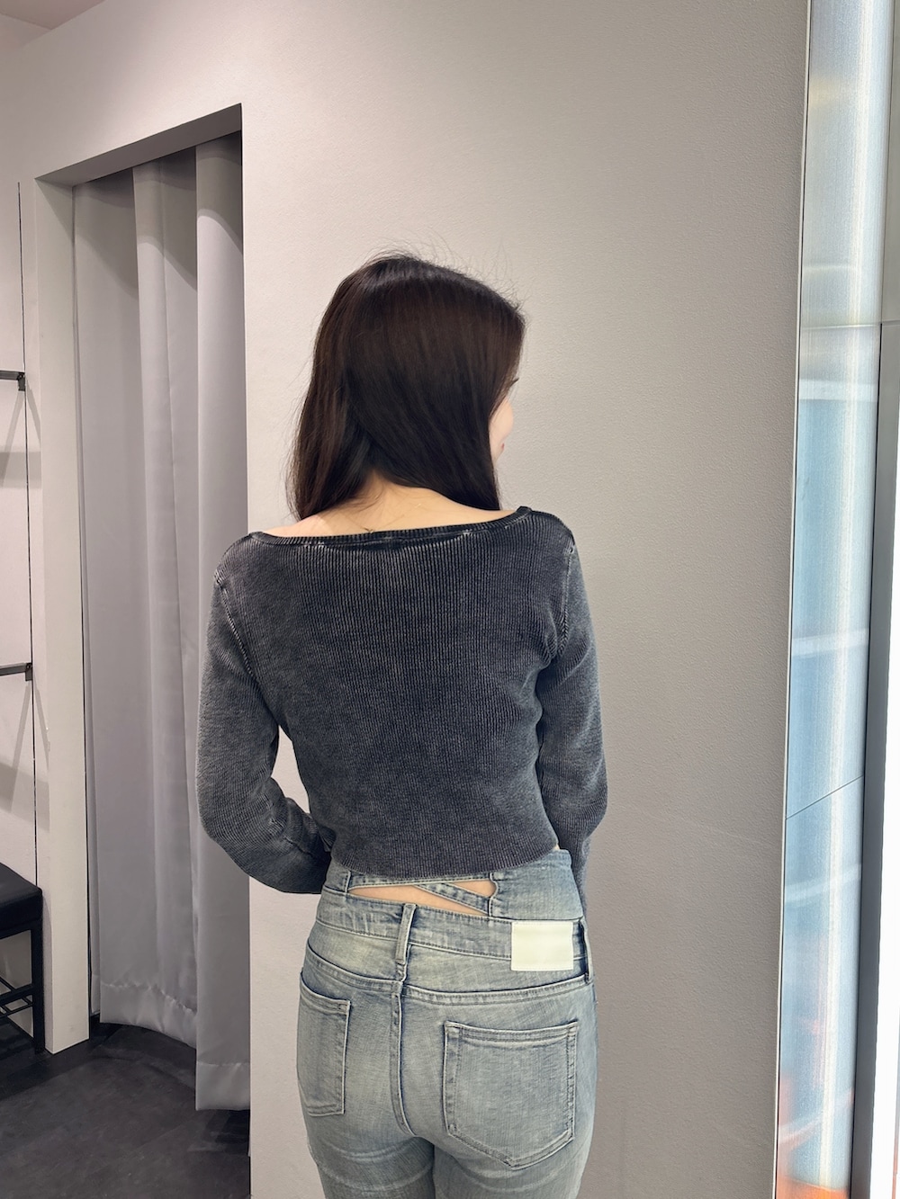 ブラック系のニット/セーター、ブルー系のデニムパンツ、ブラック系のブーツを着用したレディースの春コーディネートの6枚目の写真