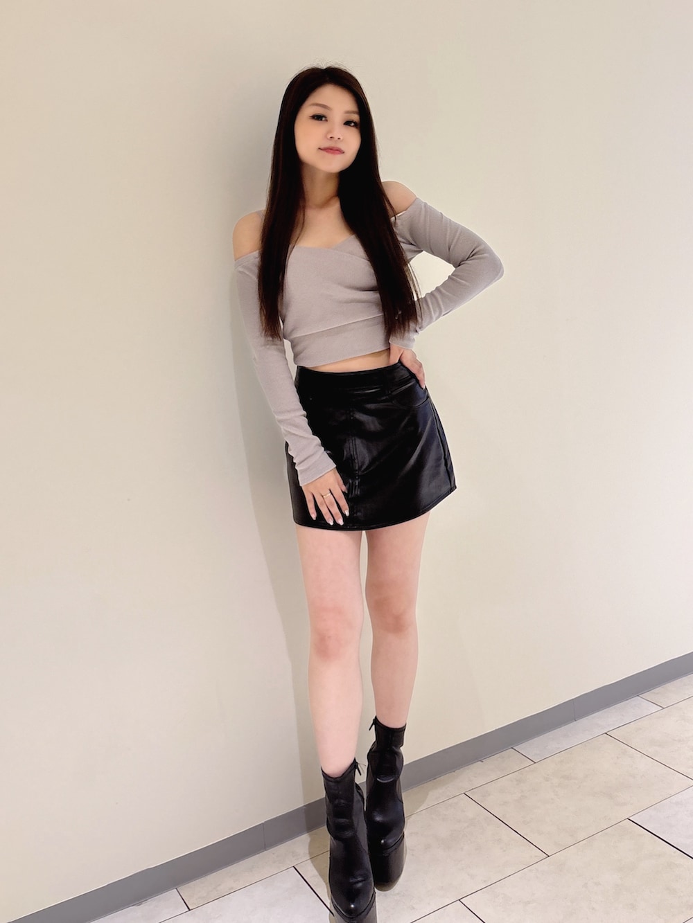 グレー系のTシャツ/カットソー、ブラック系のスカート、ブラック系のブーツを着用したレディースの秋コーディネートの2枚目の写真