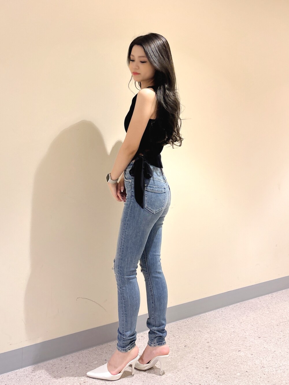 ブラック系のニット/セーター、ブルー系のデニムパンツ、ホワイト系のパンプスを着用したレディースの夏コーディネートの3枚目の写真