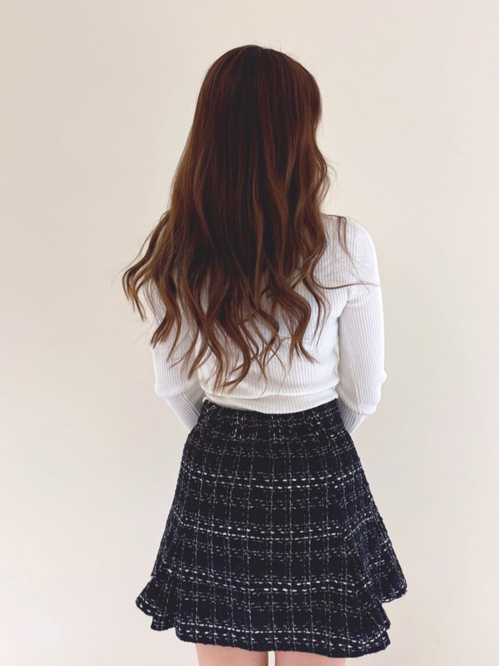 ブラック系のブーツ、ブラック系のスカート、ホワイト系のニット/セーターを着用したレディースの冬コーディネートの7枚目の写真