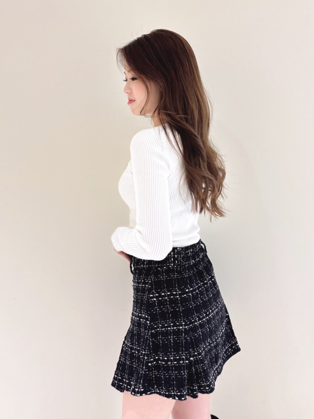 ブラック系のブーツ、ブラック系のスカート、ホワイト系のニット/セーターを着用したレディースの冬コーディネートの6枚目の写真