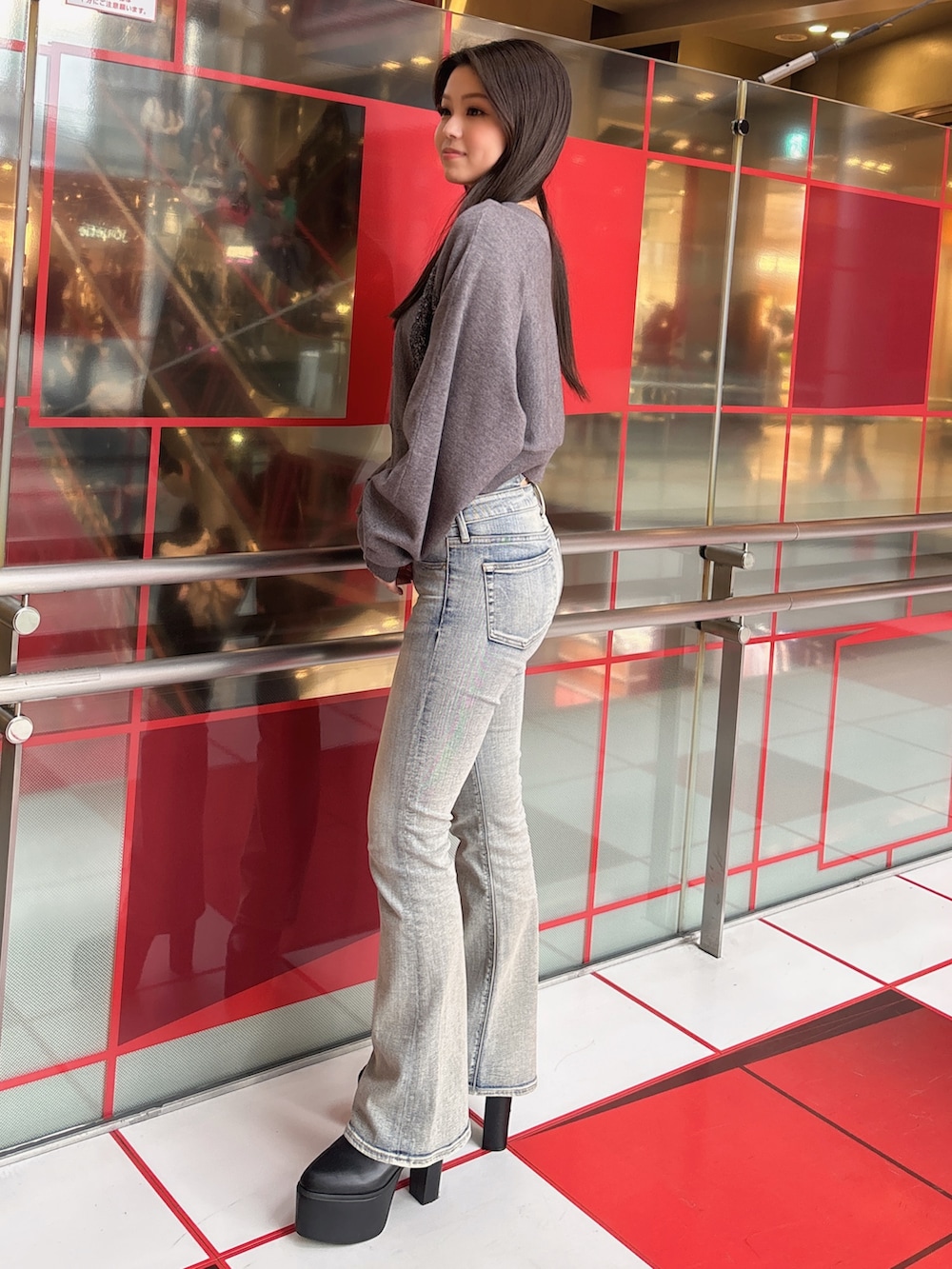 グレー系のニット/セーター、ブルー系のデニムパンツ、ブラック系のブーツを着用したレディースの冬コーディネートの2枚目の写真