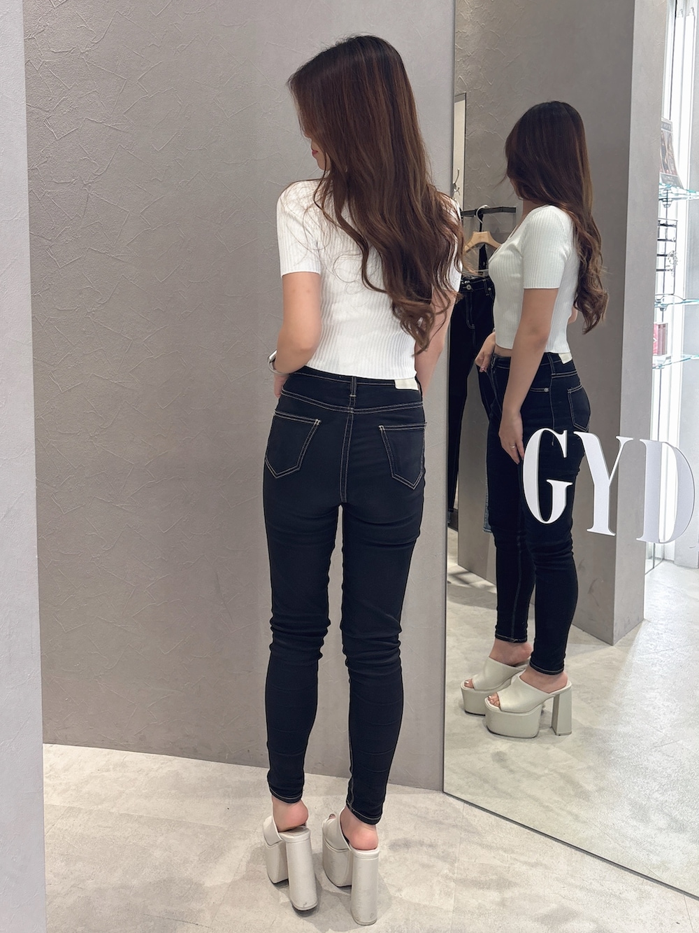 ホワイト系のニット/セーター、ブラック系のデニムパンツ、ホワイト系のサンダルを着用したレディースの夏コーディネートの3枚目の写真